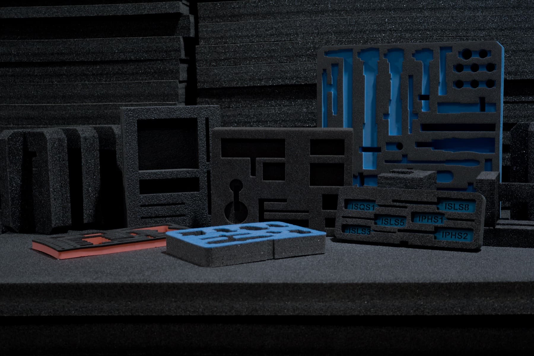 An array of custom-cut protective foam inserts in black, blue, and orange foam