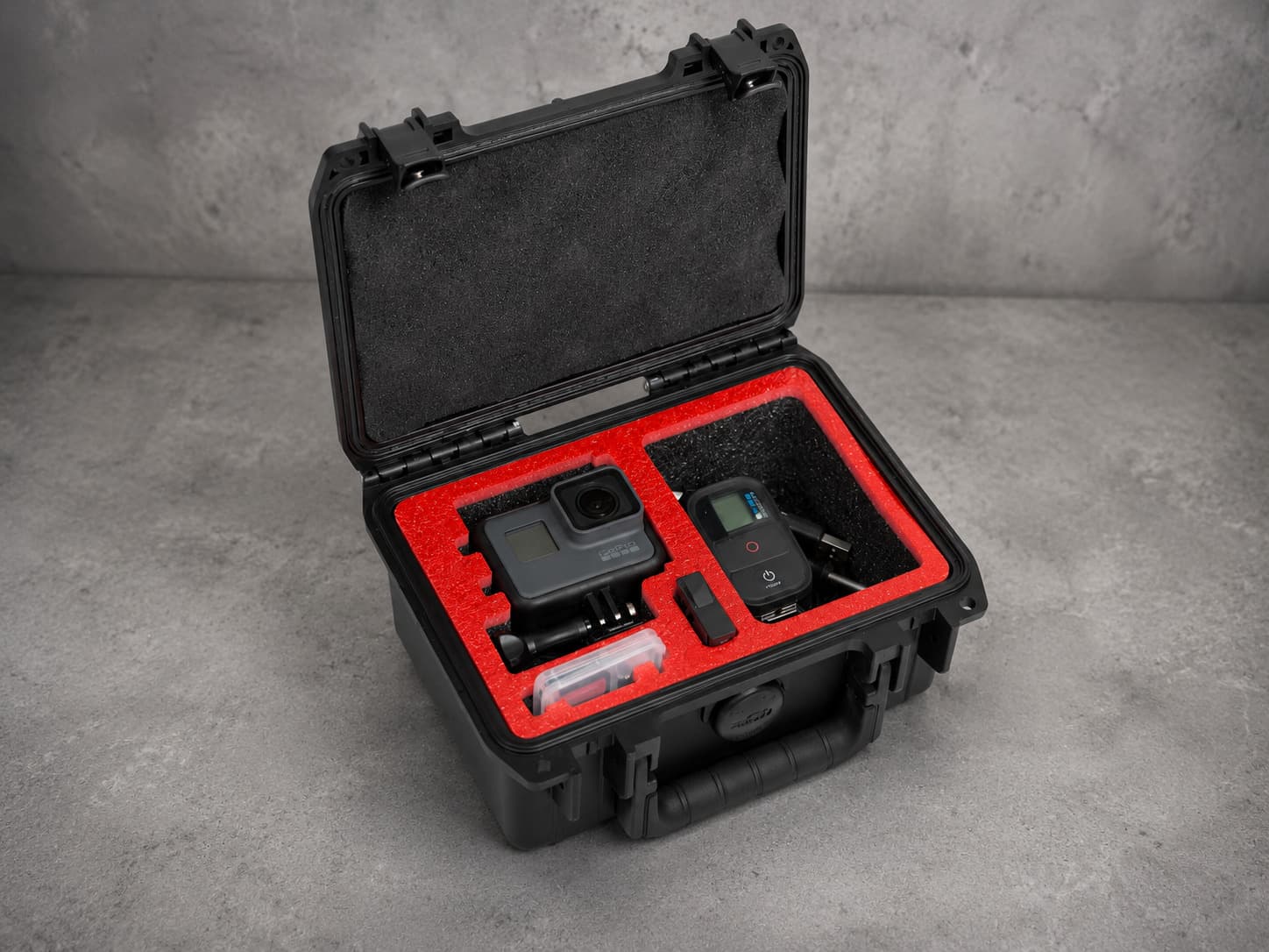 A protective case with a red foam insert holding a camera and its accessories